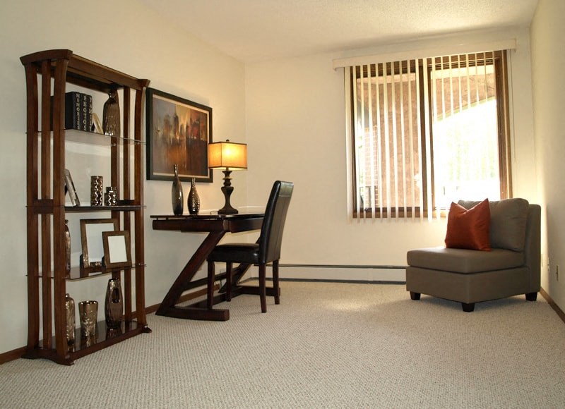 a living room with a desk and a chair and a window
