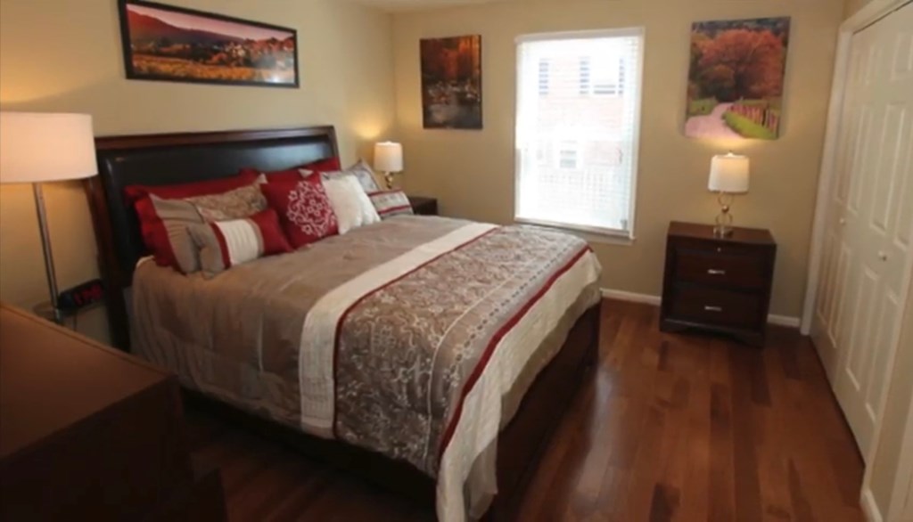 the master bedroom has a king size bed and hard wood floors