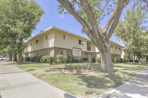 a yellow apartment building with a sign in front of it