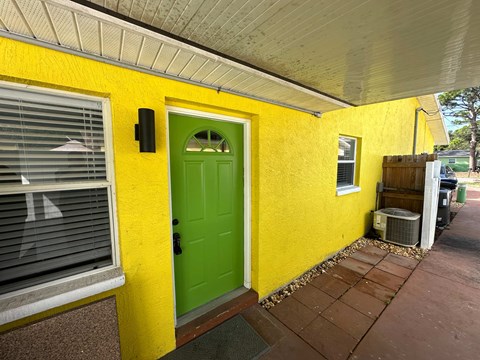 the front door of a yellow house with a green door