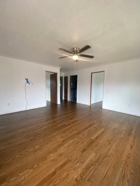 A room with wooden floors and a ceiling fan.