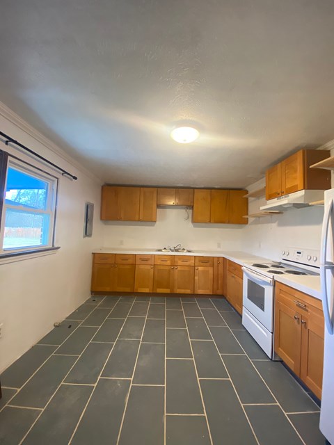 A kitchen with wooden cabinets and a white stove top oven.