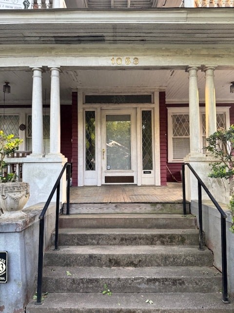 A house with a red door and a porch with a black railing.