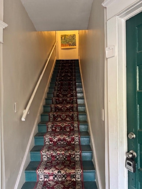 A staircase with a carpeted runner and a painting on the wall.