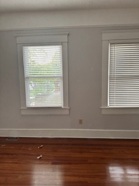 A room with two windows and wooden floors.
