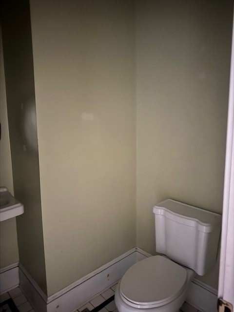 A white toilet in a bathroom with a white toilet paper holder.