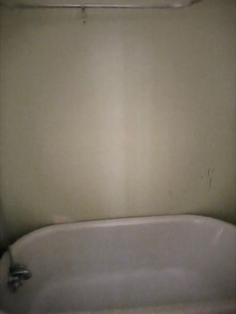 A white bathtub with a silver faucet is in the corner of a bathroom.