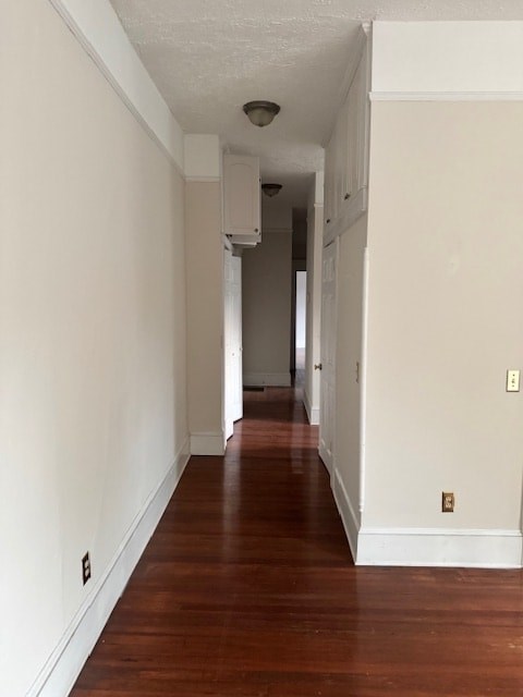 A long hallway with wood floors and white walls.