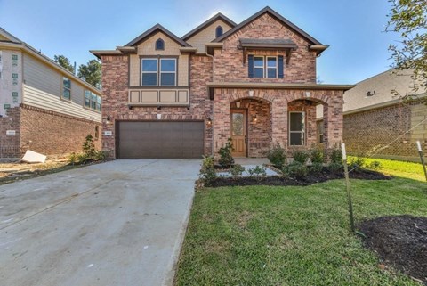 A two-story brick house with a garage and a driveway.