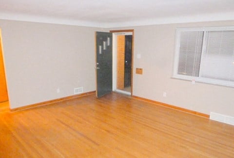 an empty living room with wood floors and a door to a closet