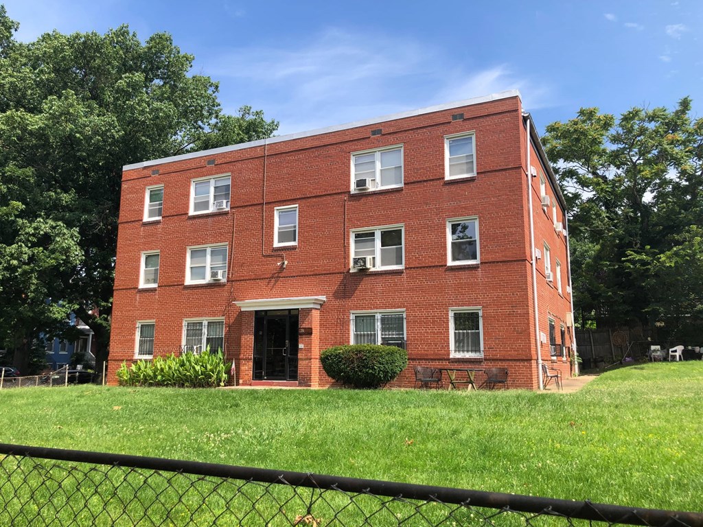 a red brick building on a hill with a fence