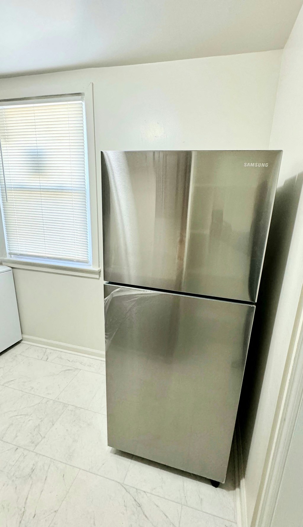 a kitchen with a stainless steel refrigerator and a window