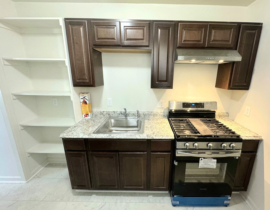 a kitchen with brown cabinets and a sink and a stove