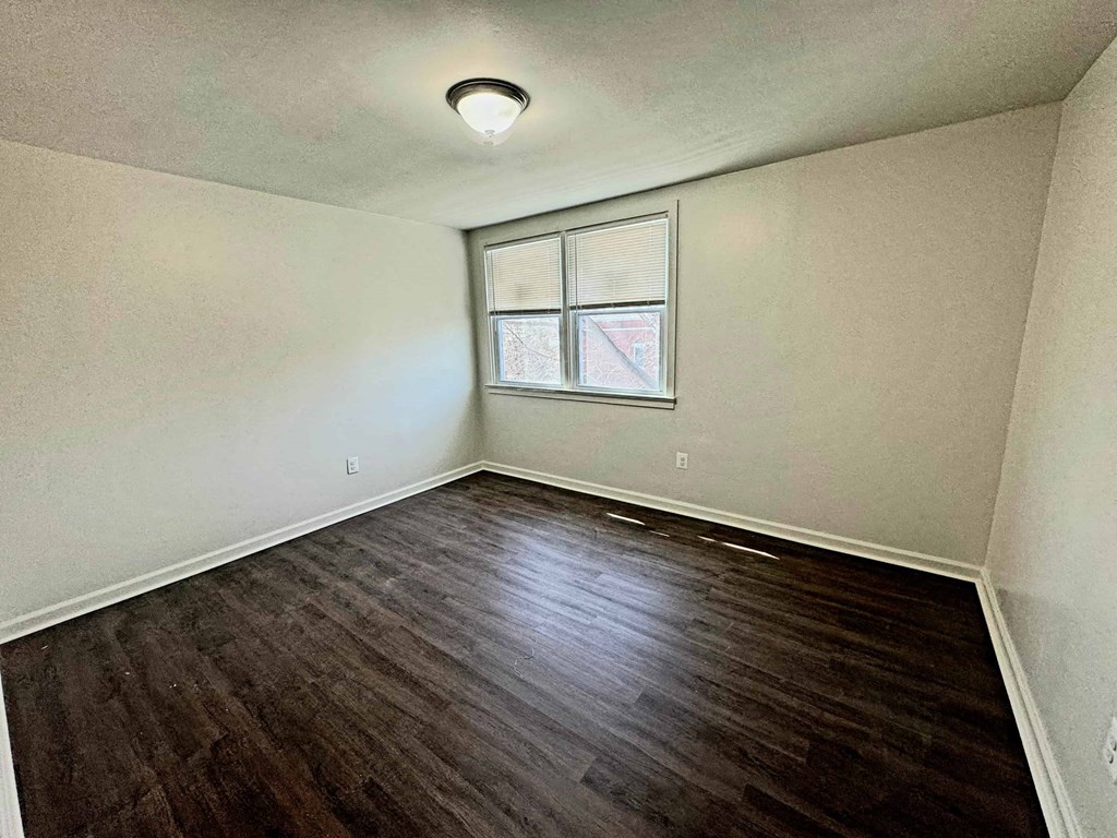an empty room with hardwood floors and a window