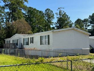 a white mobile home with a fence in front of it