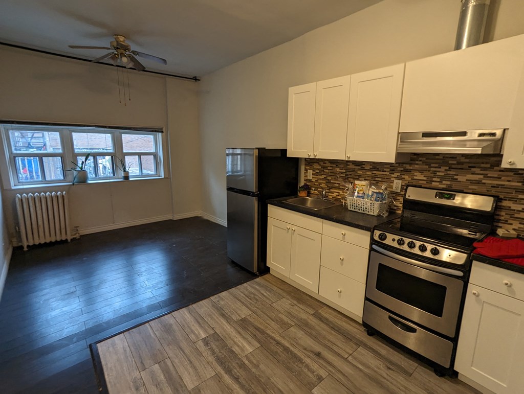 an empty kitchen with stainless steel appliances and white cabinets
