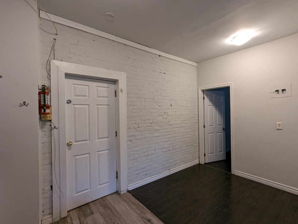 an empty room with a white door and a white brick wall