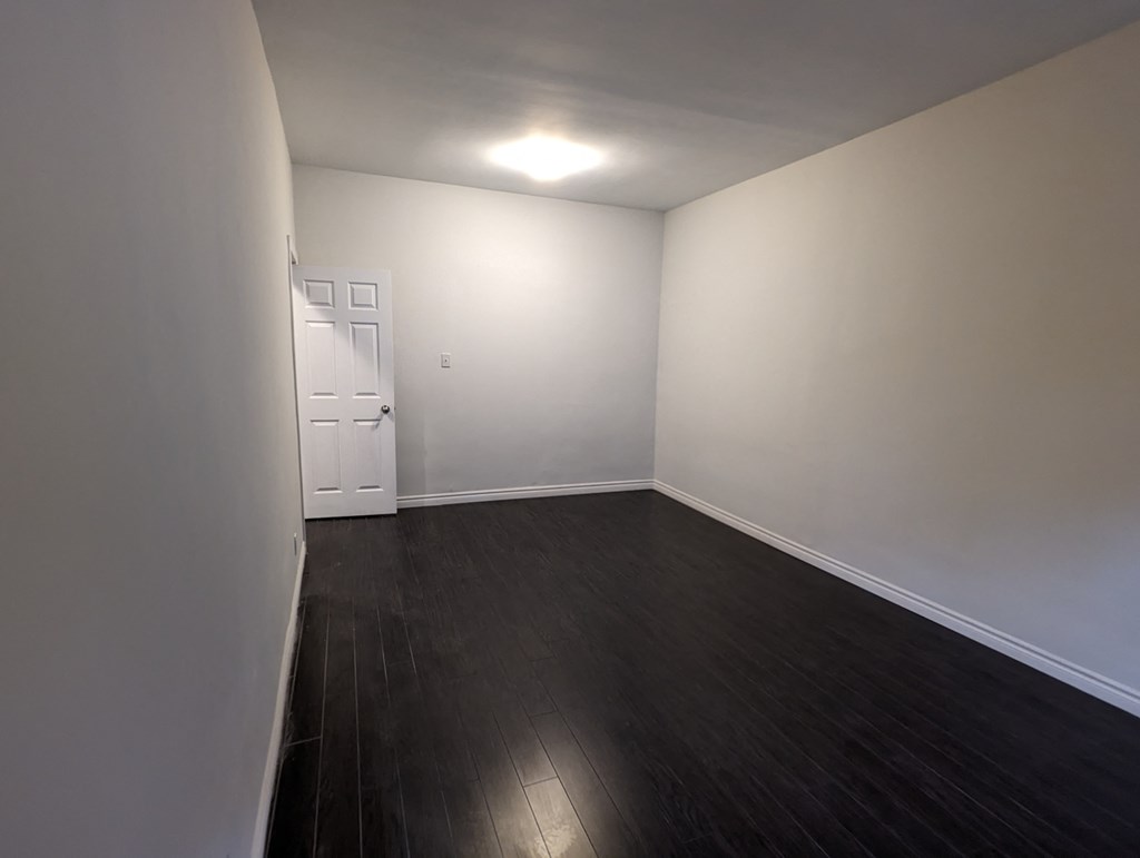 an empty living room with wood floors and white walls