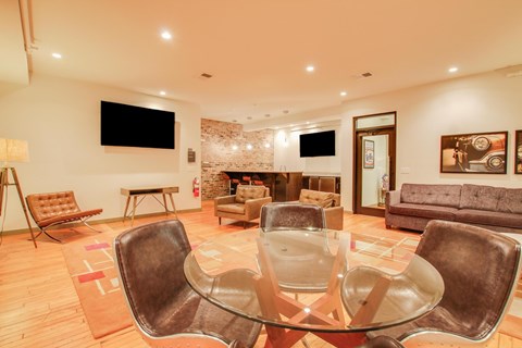 A modern living room with a glass table and brown leather chairs.