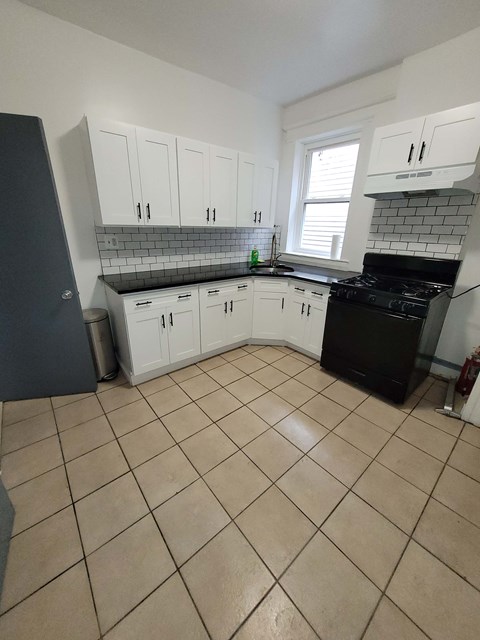 A kitchen with black appliances and white cabinets.