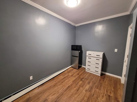 A kitchen with a refrigerator, microwave, and a white drawer cabinet.