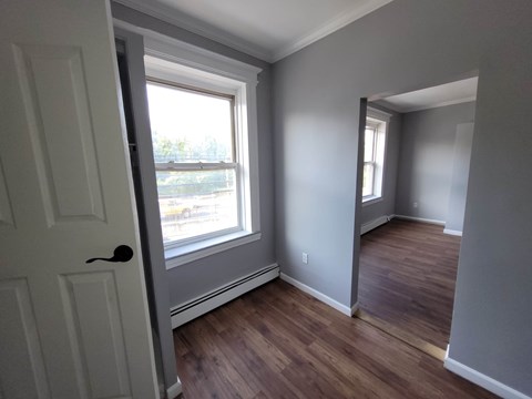A room with a white door and a window with a view of the street outside.