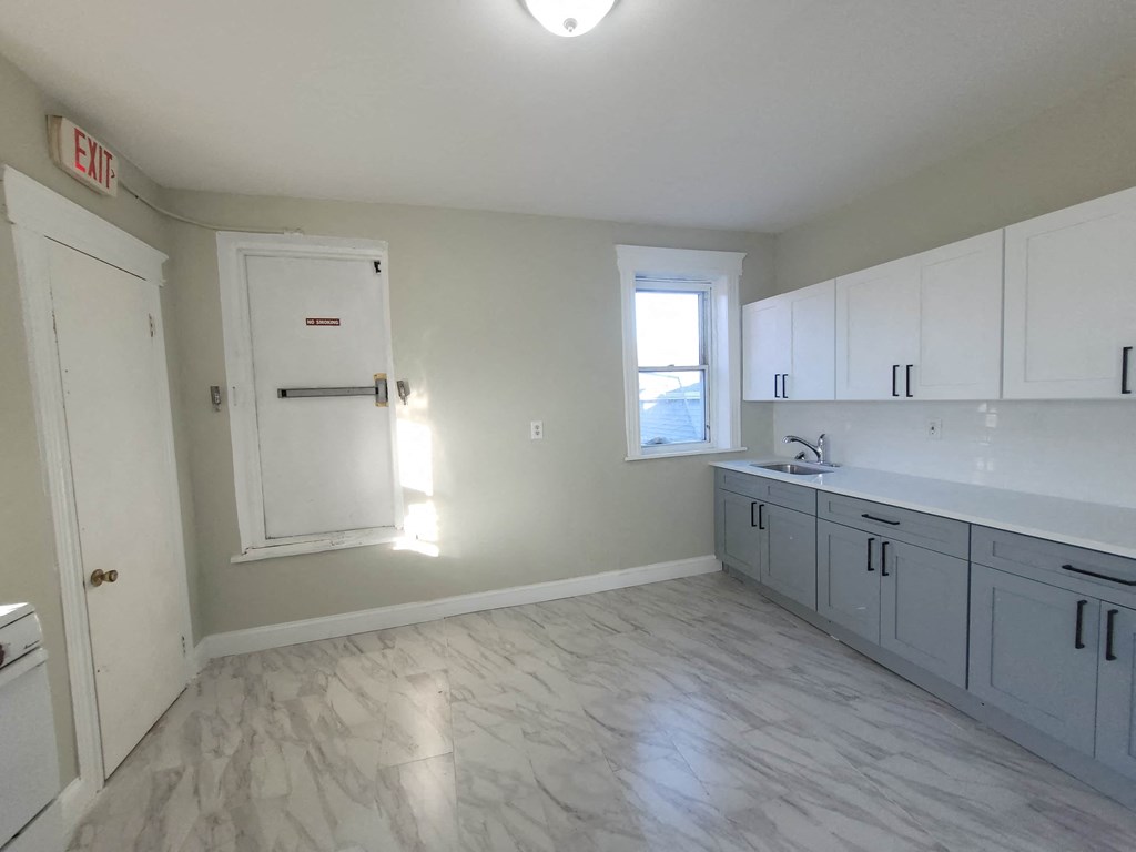 an empty kitchen with white cabinets and a window