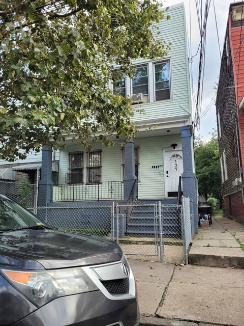 A car is parked in front of a blue house.