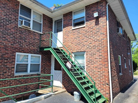 A red brick house with a green staircase.