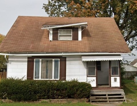 a small white house with a brown roof