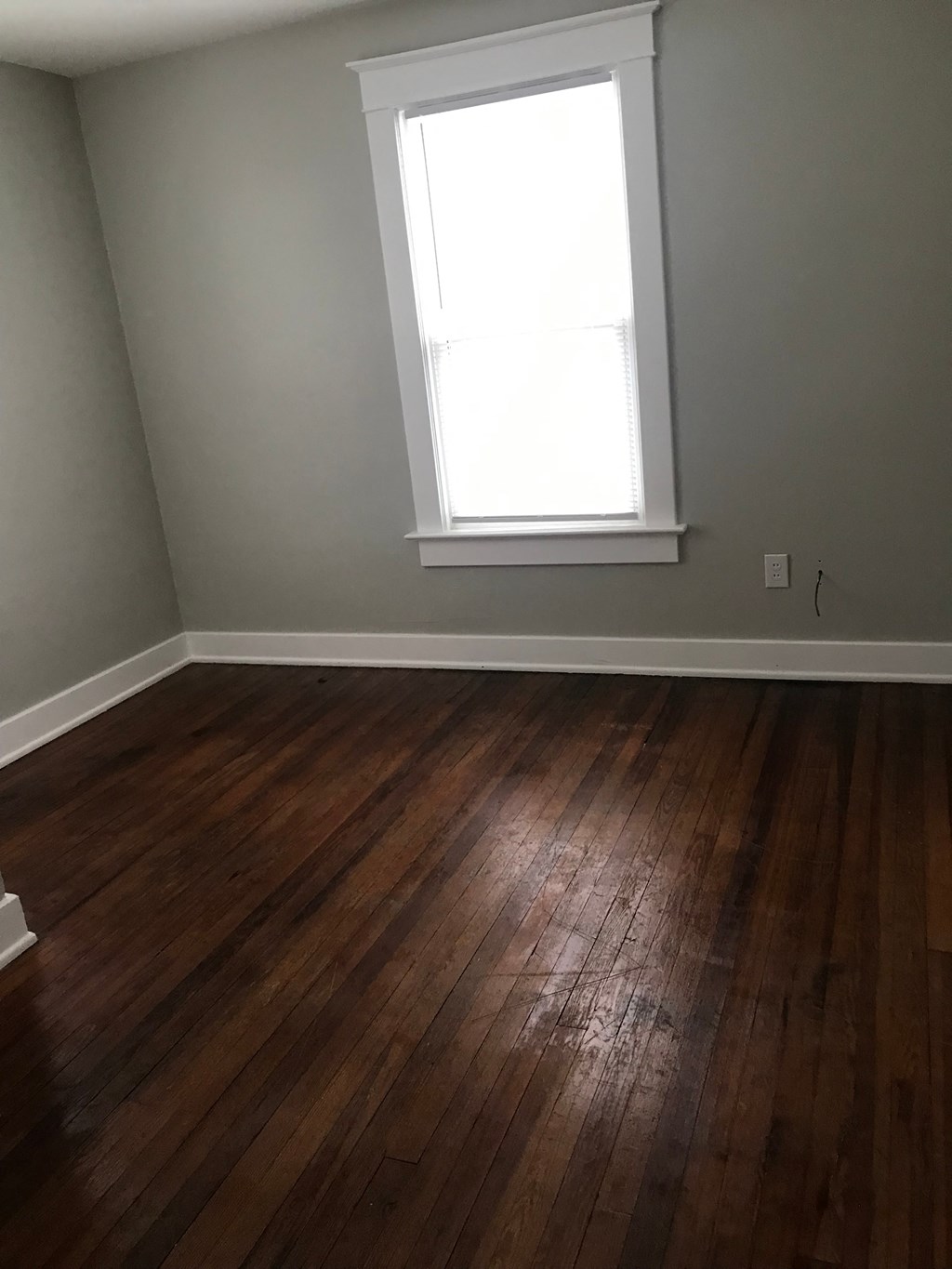 an empty room with wooden floors and a window