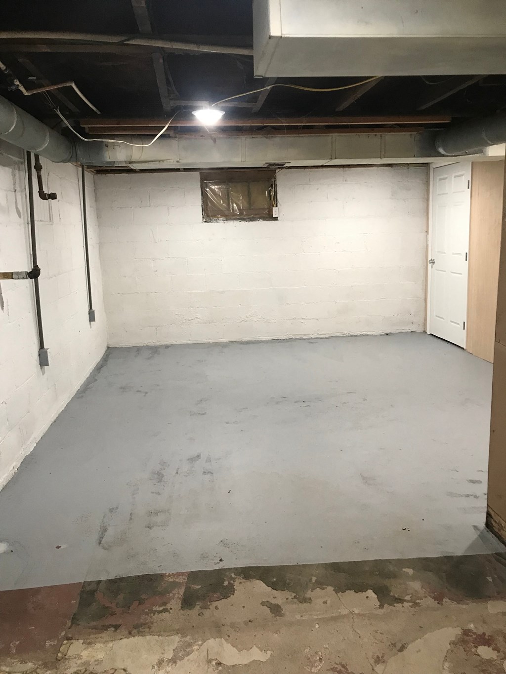 a white basement with a concrete floor and white brick walls