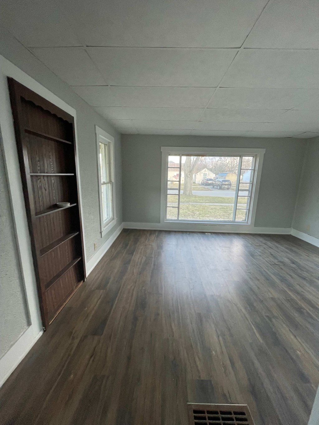 an empty living room with wood floors and a window