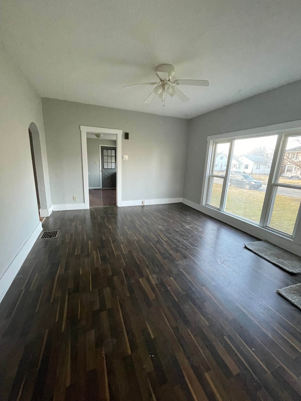 an empty living room with wooden floors and a ceiling fan