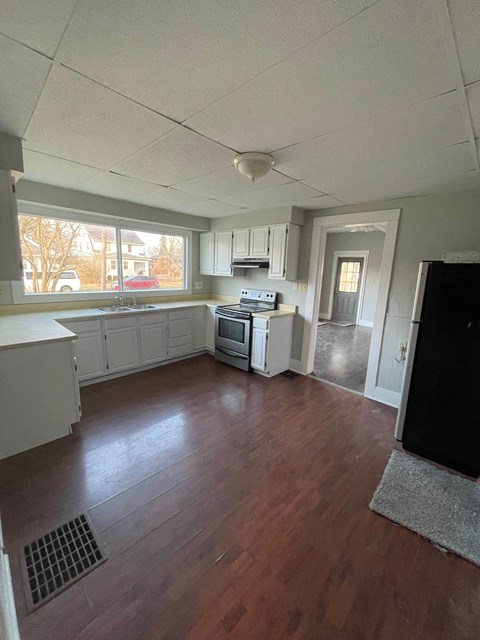 an empty kitchen with wood floors and white cabinets