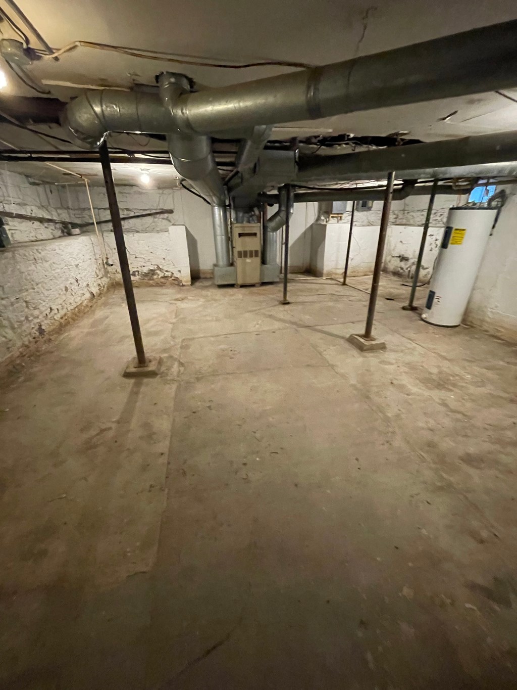 the basement of a building with pipes and a concrete floor