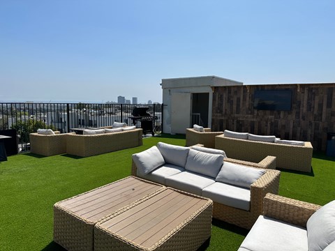 a roof top lounge area with couches and tables on a rooftop