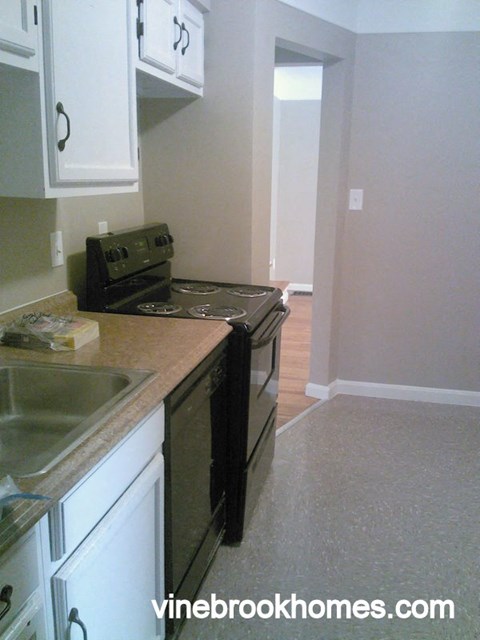 A kitchen with black appliances and white cabinets.