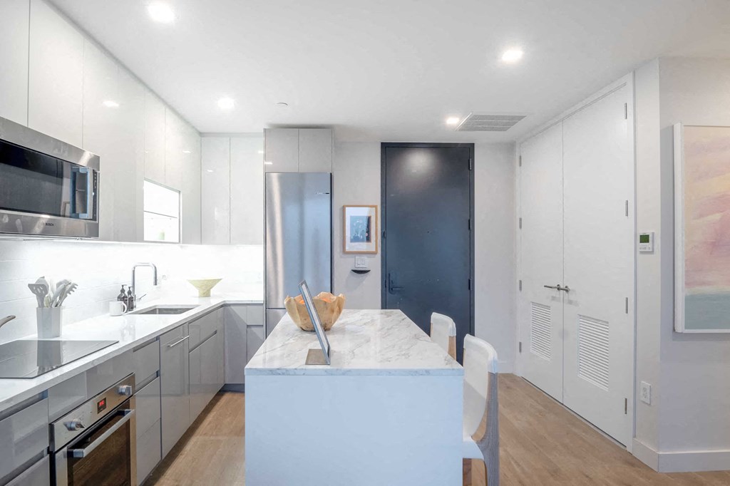 a kitchen with white cabinets and a marble counter top