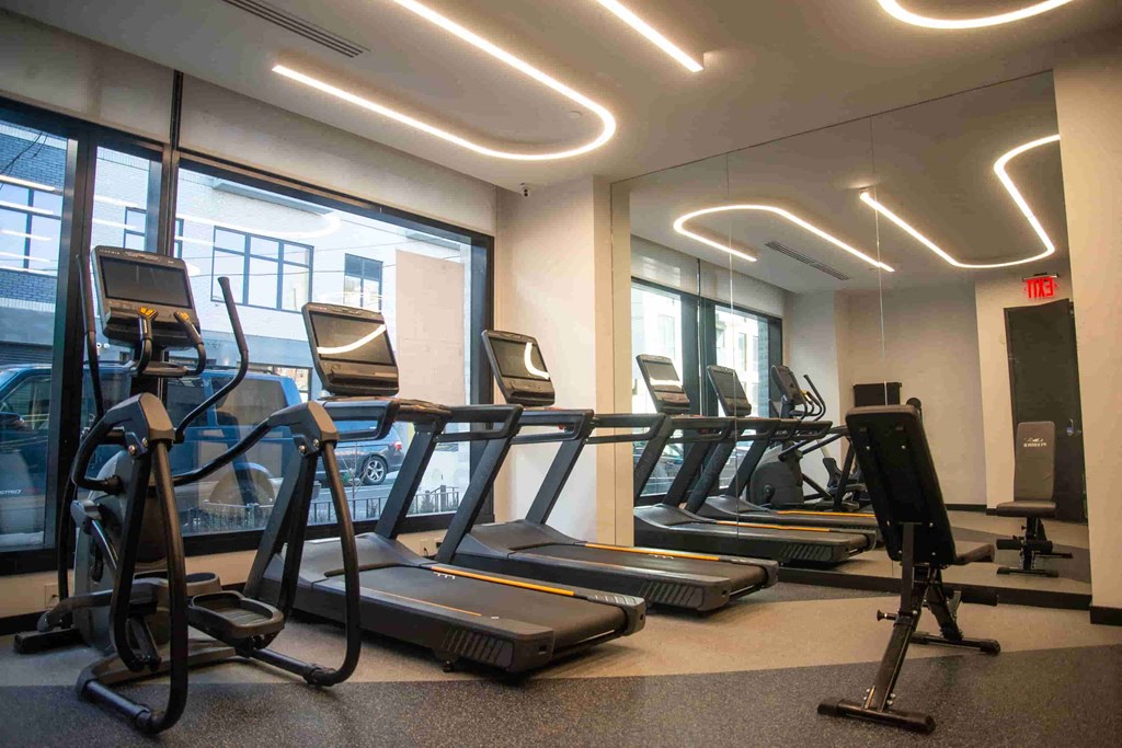 a gym with cardio equipment and windows in a building