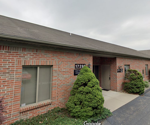 the front of a brick building with a porch and a driveway