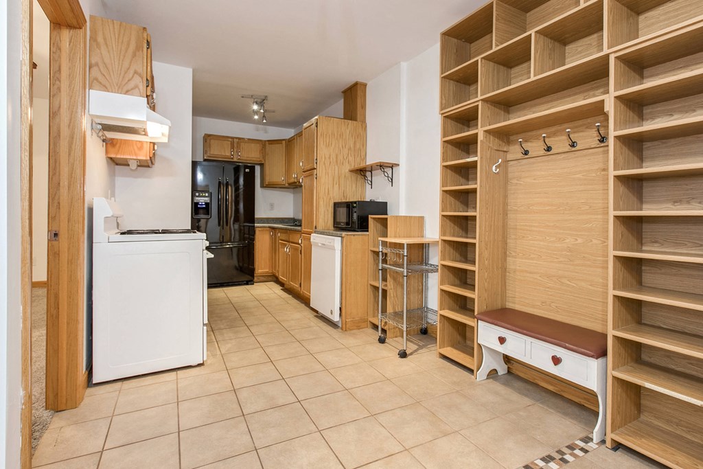 a kitchen with a white refrigerator and wooden shelves