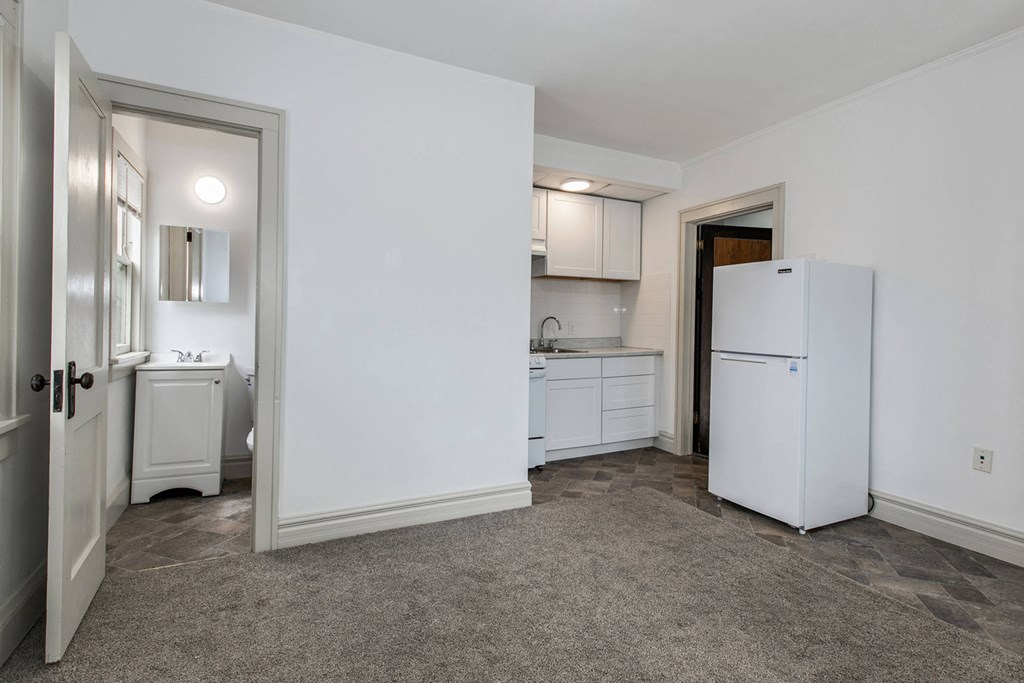 a white kitchen with a refrigerator and a sink and a doorway
