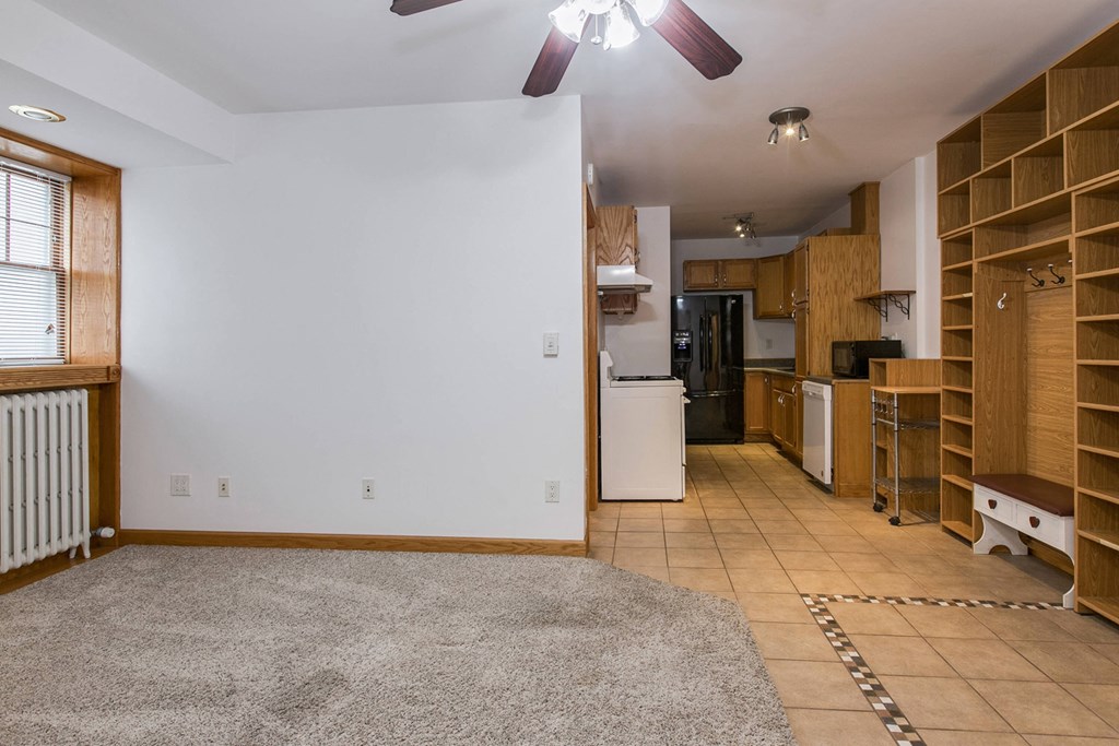 a kitchen and living room with a carpeted floor and wooden shelves