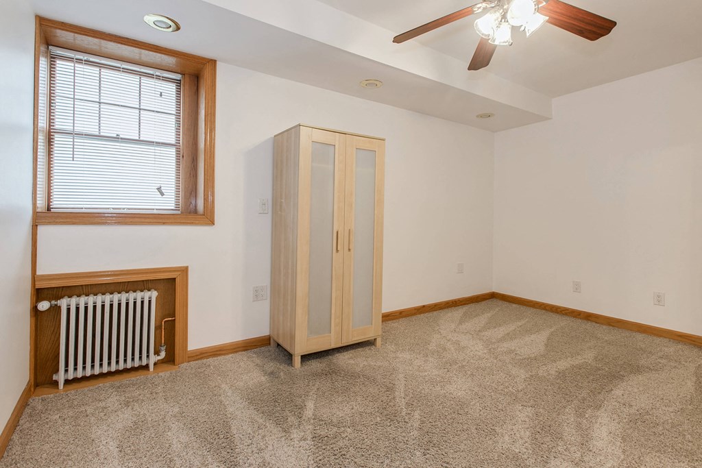 an empty living room with a radiator and a cabinet in the corner