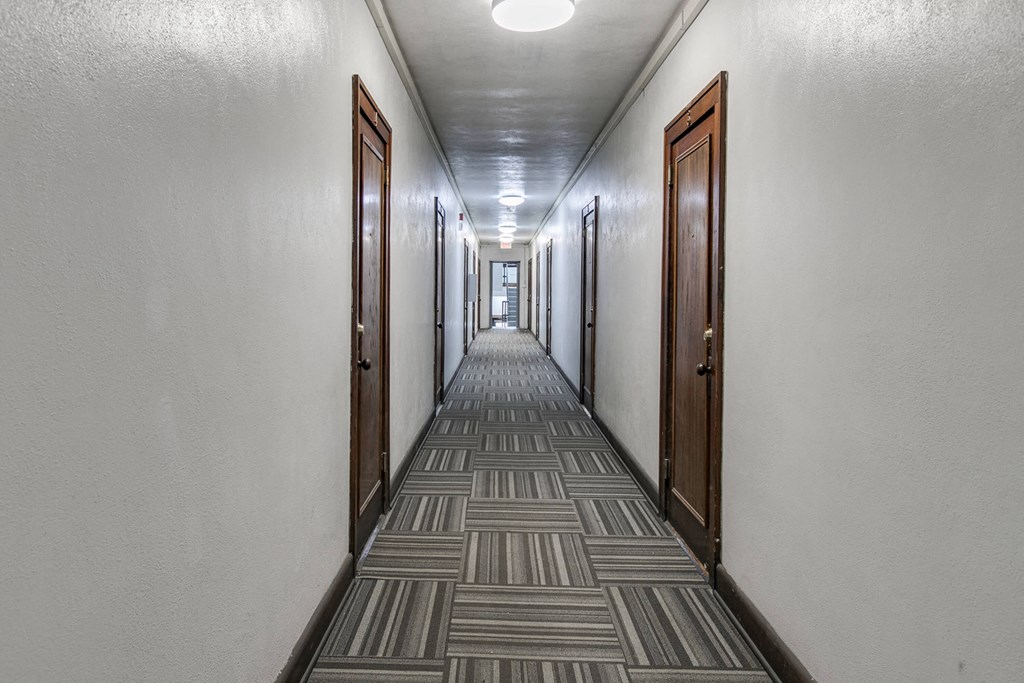 a long hallway with doors and a carpeted floor