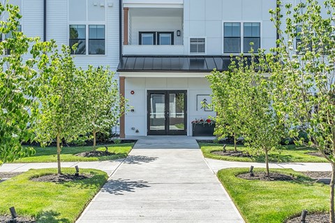the front of a white building with trees and a sidewalk