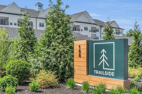 a building with a sign that says trailside in front of trees