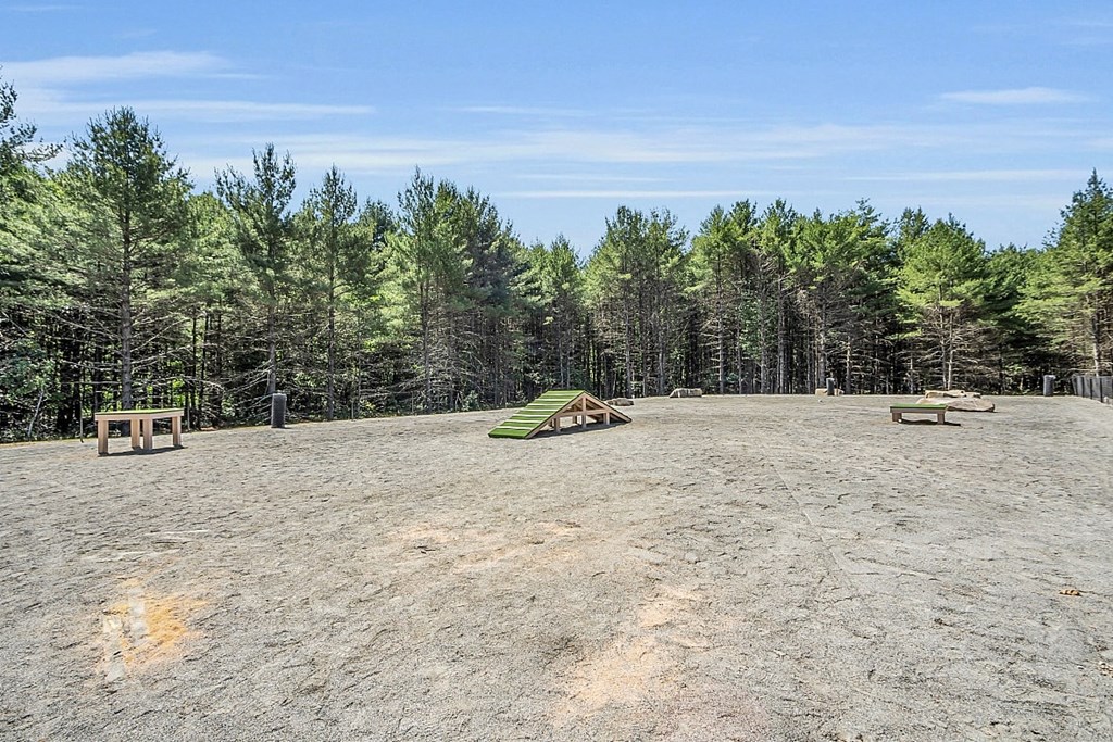 a large dirt field with benches and trees in the background