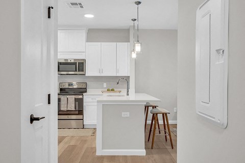 a kitchen with white cabinets and a white island with stools